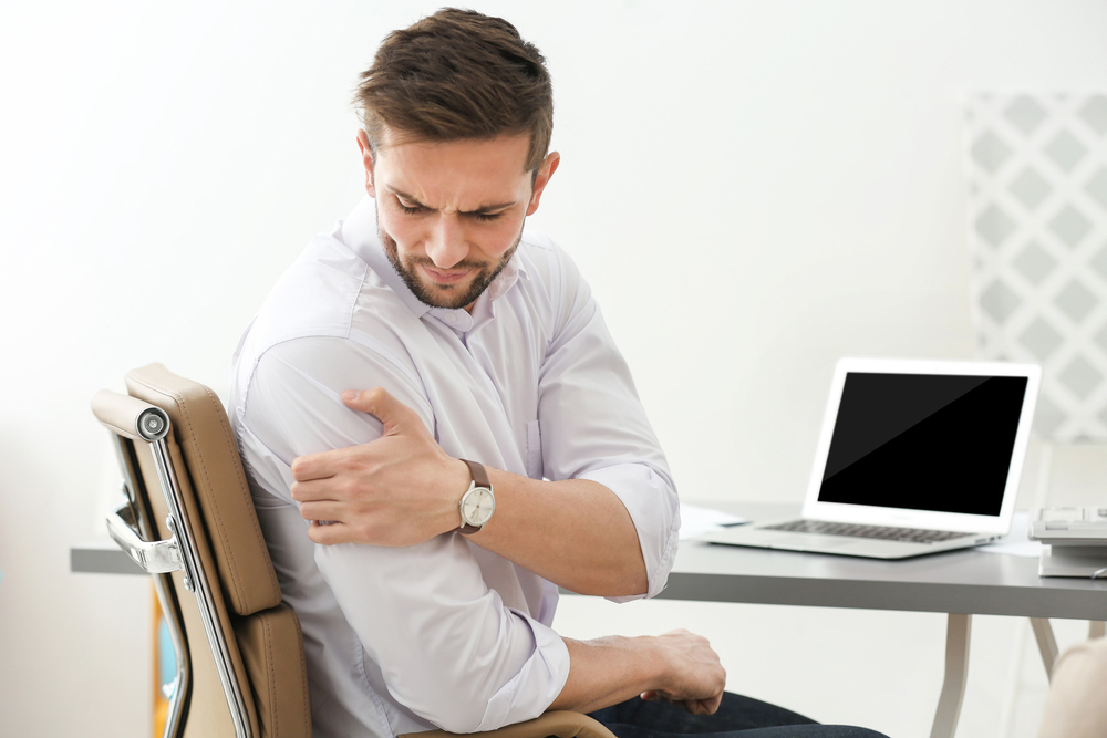 Man with shoulder pain in his office at work